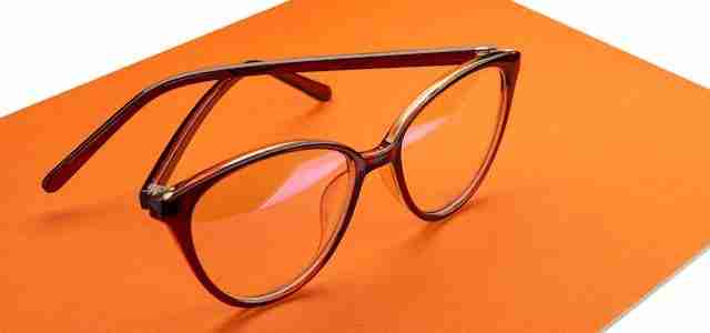 a pair of black rimmed eyeglasses on orange background