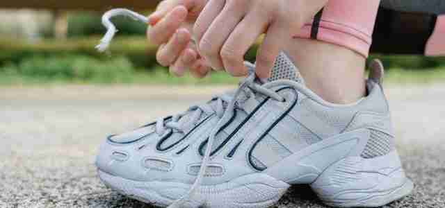 person tying lace on trainer before building sustainable morning running routine